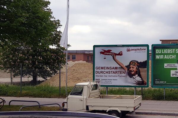 Plakatwand mit peoplefone Werbung an einer Straße.