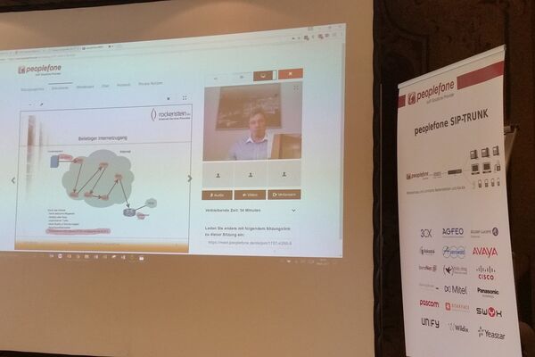 Bildschirmansicht auf Leinwand. Präsentation wird über Videokonferenz durchgeführt.