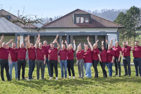 peoplefone Team steht vor einem Gebäude und winkt in die Kamera.