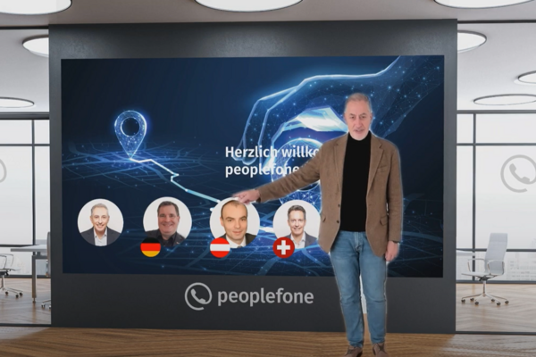 Eine Person steht vor einer Präsentationswand und zeigt auf eine abgebildete Folie.