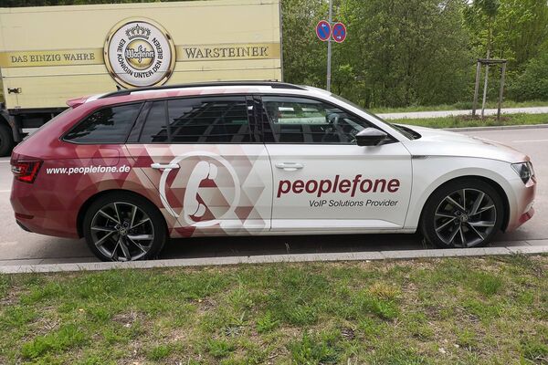 Fahrzeug der peoplefone steht vor einem Bierlaster.