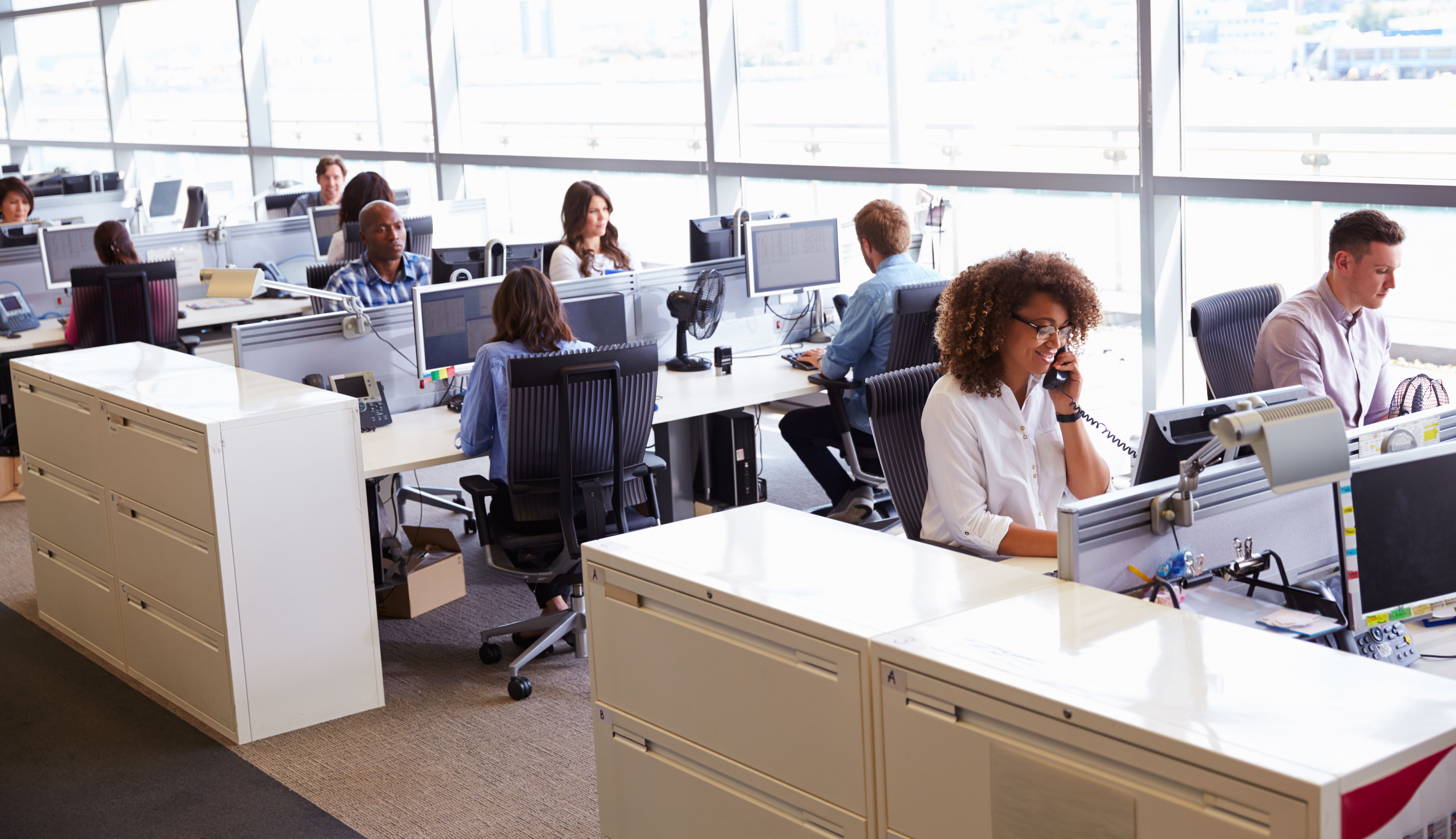 Mehrere Personen sitzen telefonieren in einem Callcenter.