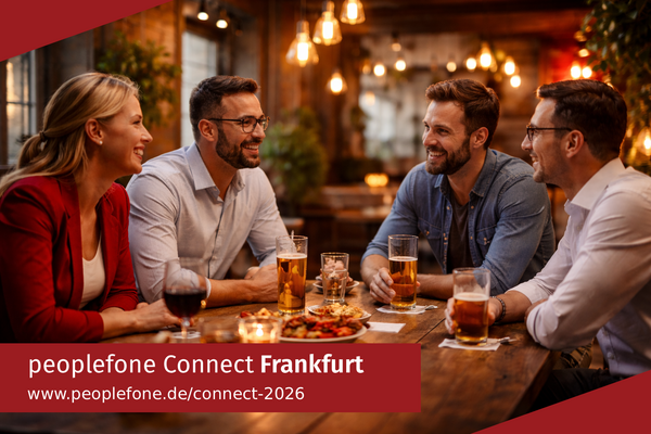 peoplefone Connect Frankfurt. Personen sitzen an einem Holztisch und unterhalten sich.