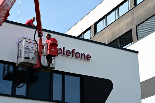 peoplefone Logo wird mit einem Kran an die Außenwand angebracht.